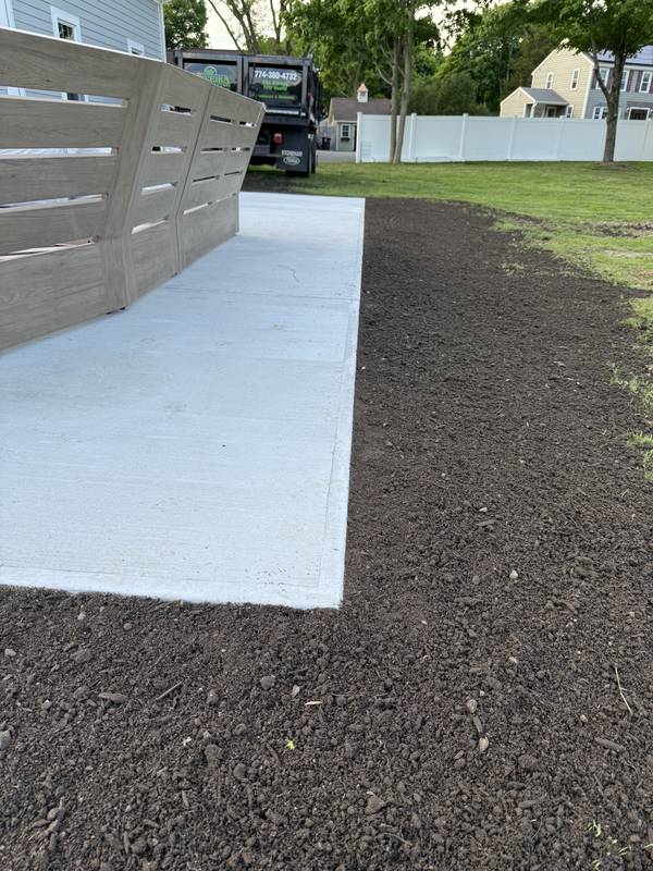 Concrete walkway with new loam along the fence