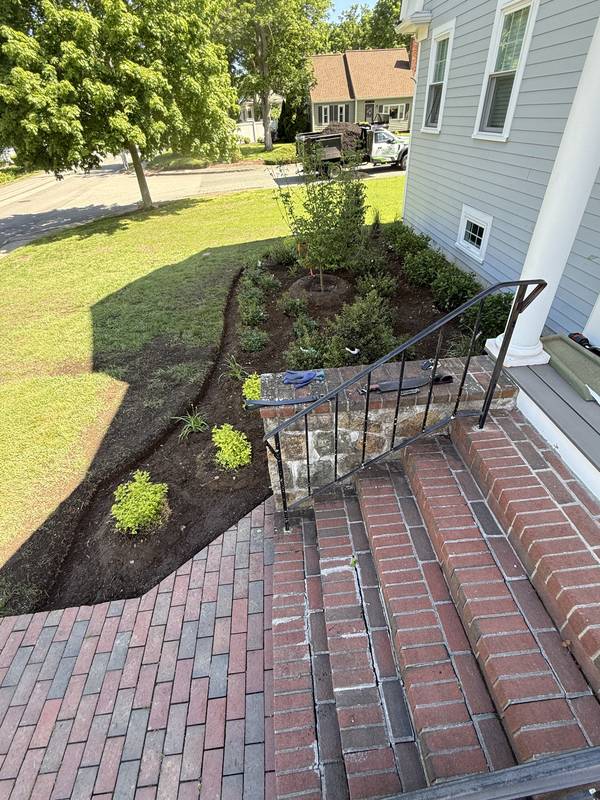 Brick stoop framed by new beds and a manicured lawn