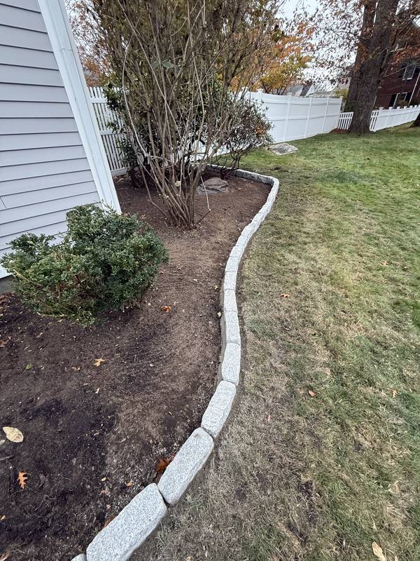 Granite edging wrapping a side-yard planting bed