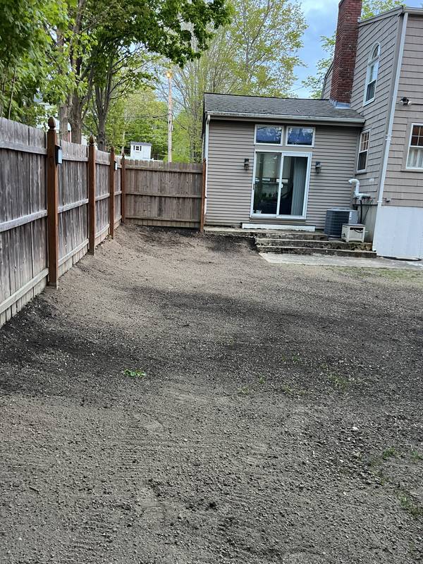 Loam graded along the fence line and patio