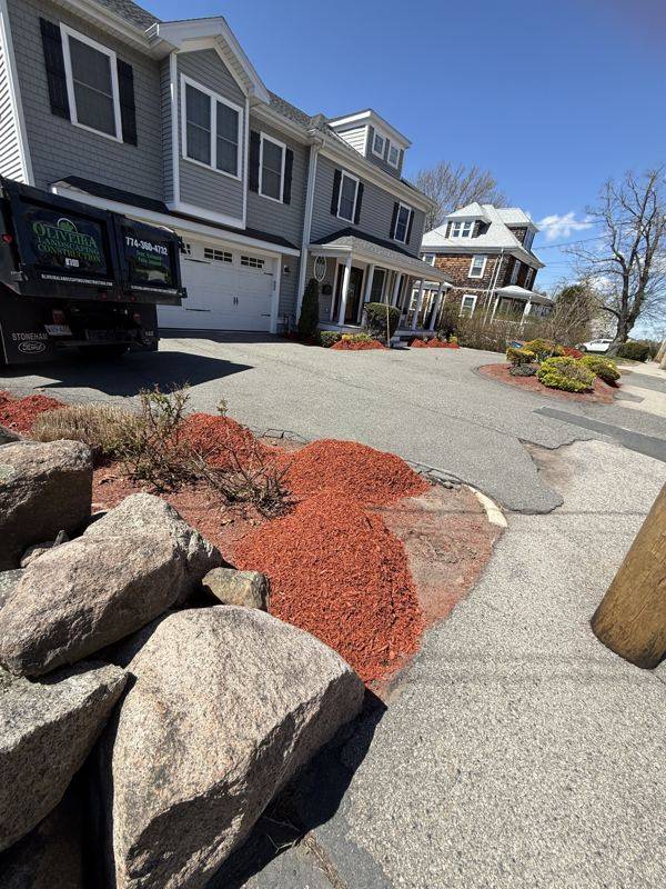 Boulder accents and sculpted shrubs set into fresh red mulch