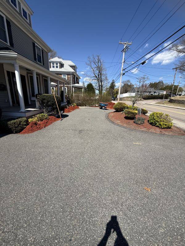Manicured front beds and crushed-stone driveway at a colonial home