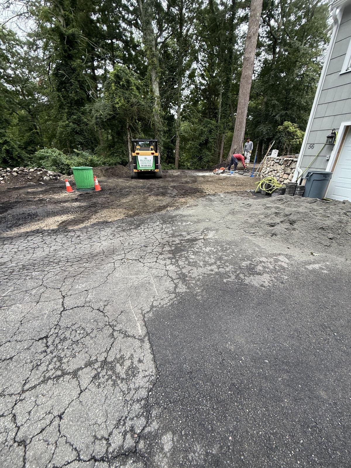 Cracked asphalt and bare soil before the hardscape rebuild