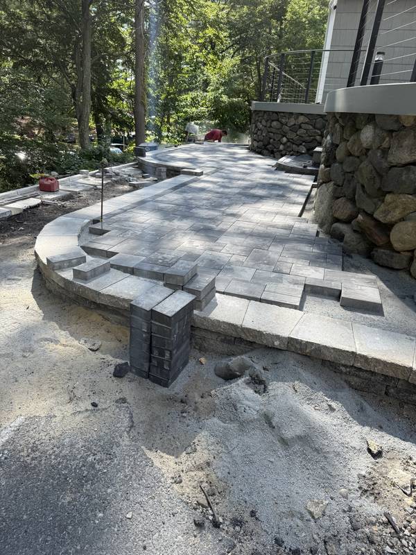 Laying the paver field and curved step against the fieldstone wall