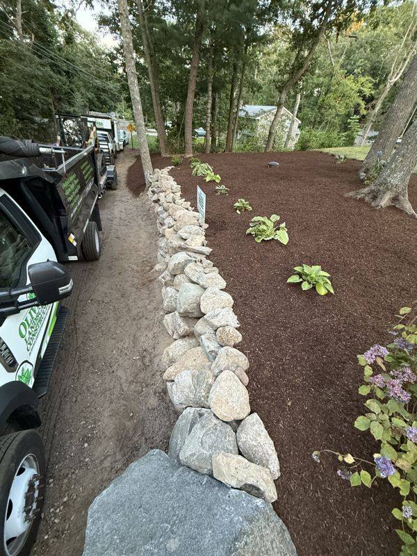 Curved stone retaining wall framing the new walkway and garden beds