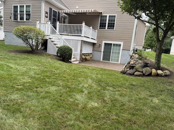 Backyard view of the new patio, boulder bed and lawn