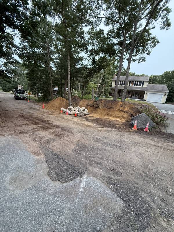 Torn-up driveway edge and slope before regrading